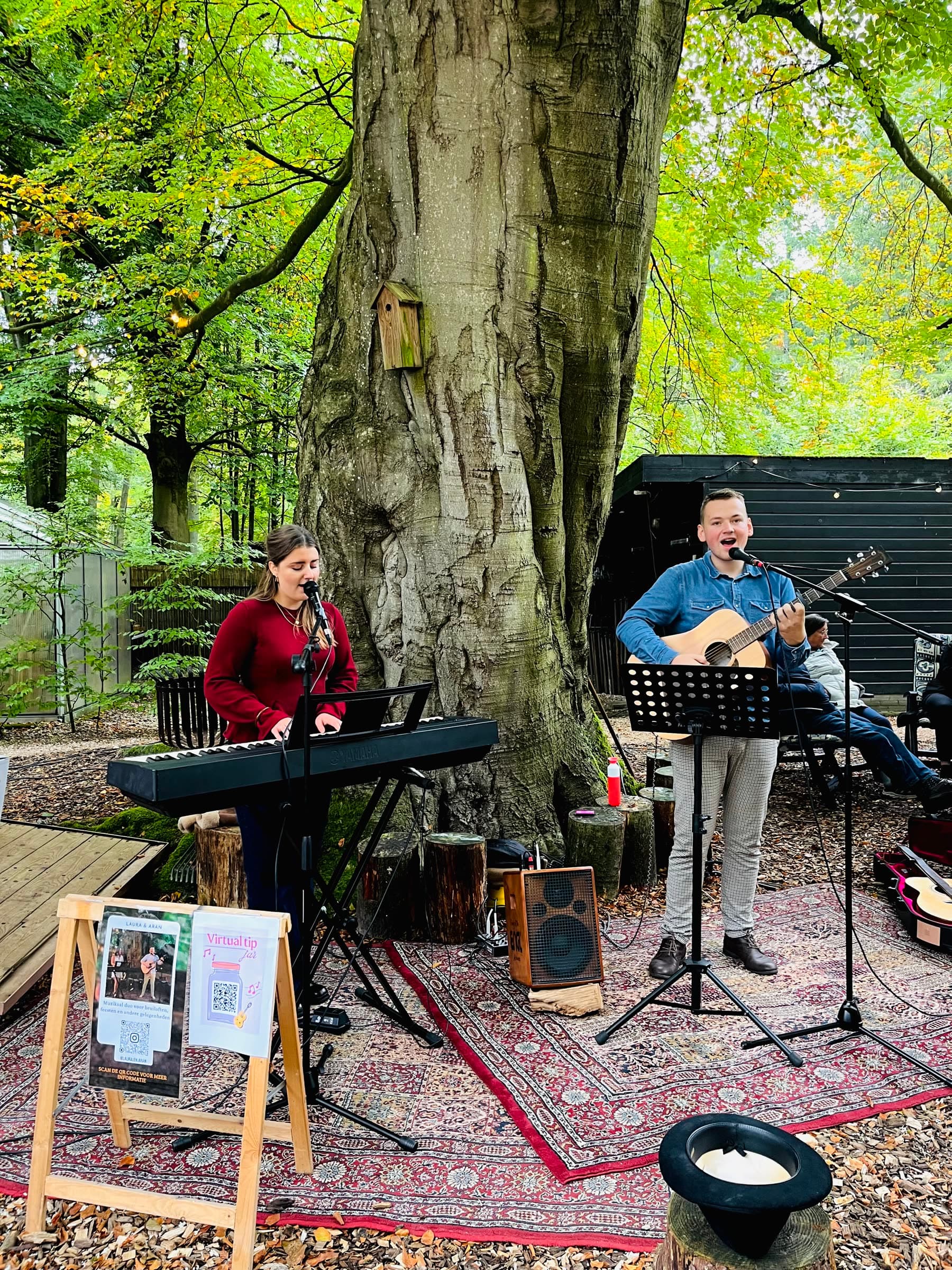 Laura en gastgitarist Aran spelend in het bos op een Perzisch tapijt