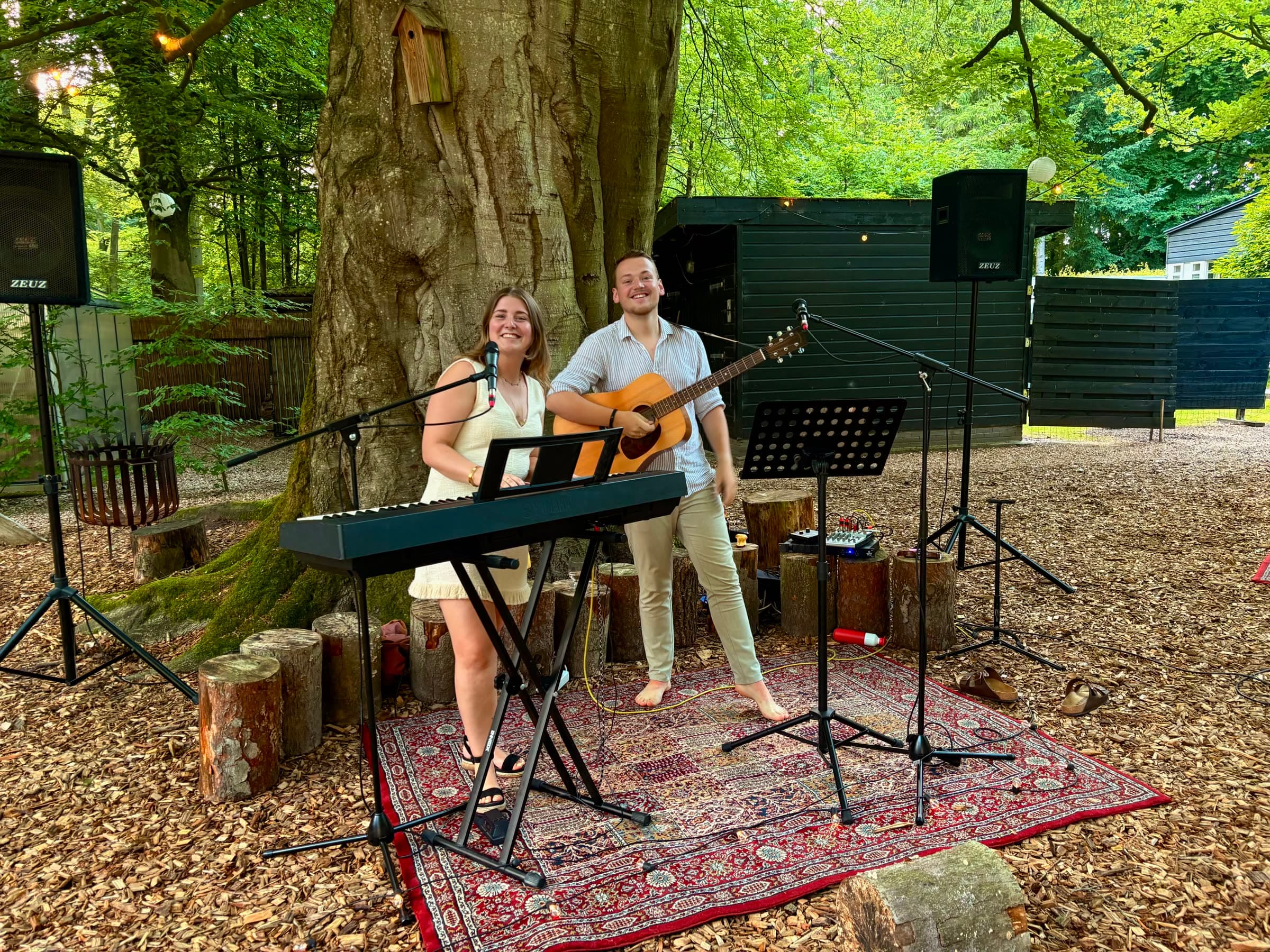 Het duo lacht naar elkaar tijdens een set in een bosrijke setting